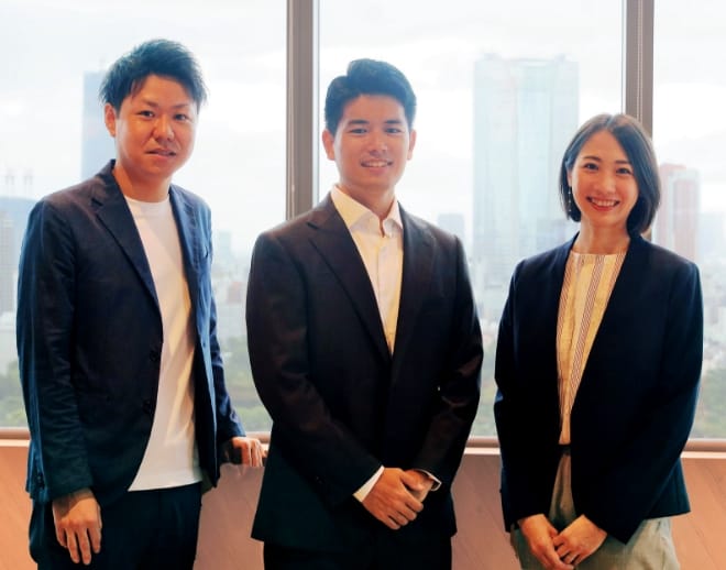 窓を背にビジネススーツの男性二人と女性一人が写っている画像